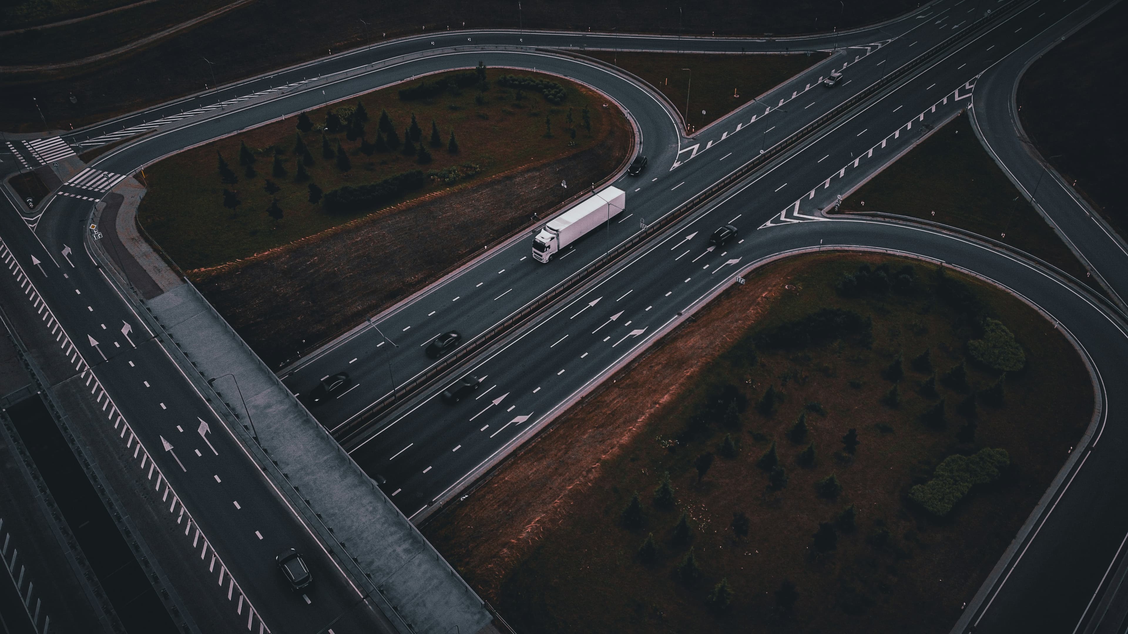 Aerial view of a highway interchange with a white semi-truck in transit